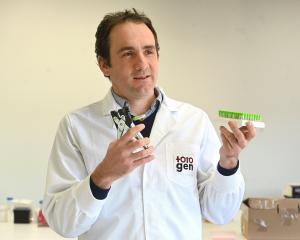 TotoGen co-founder Tim Hore displays an ear punch designed to easily collect DNA samples from...