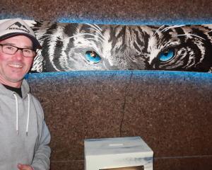 Recycled snowboard exhibition organiser Jase John with a white tiger painted on a board by...