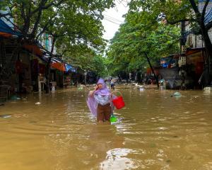 A woman wades through a flooded street following the impact of Typhoon Yagi, in Thai Nguyen City,...