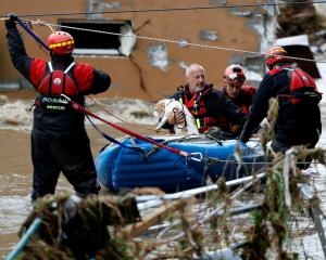 A man holds a dog as he is aided by rescuers on a flooded street in Jesenik,&nbsp;Czech&nbsp...