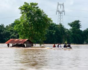 Rescuers ride a boat through a flooded area, searching for stranded people in Taungnoo city,...