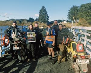 A group of enduro supporters cross the Clutha on the Tuapeka punt, piloted by Tom Jones in high...