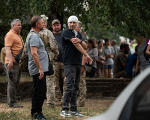 People stand near the Poltava Military Institute of Communications, the site of a Russian missile...