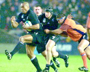 Jonah Lomu (L), followed by teammate Josh Kronfeld, breaks through a tackle from Scotland's Budge...