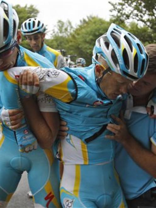 Alexande Vinokourov of Kazakhstan, second right, is helped by his teammates after crashing during...