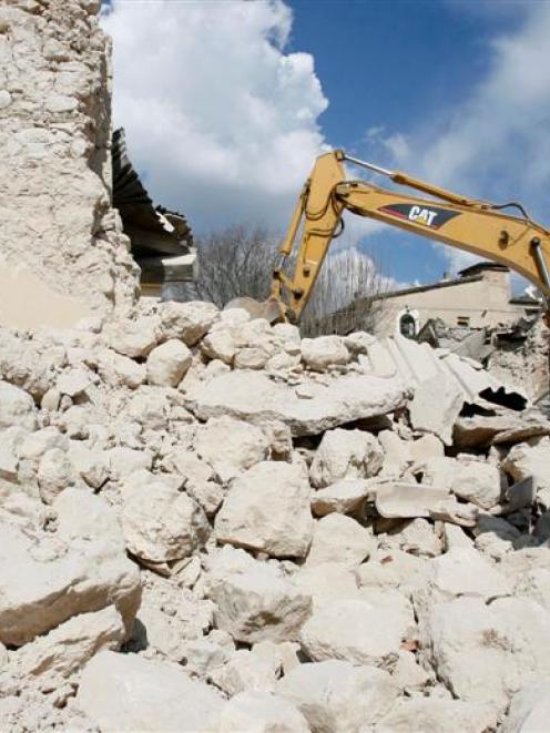 An excavator digs through the rubble of collapsed church building, in the village of Castelnuovo,...