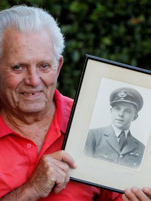 Aubrey Bills (91) holds a photograph of himself in uniform as a 20-year-old, while recounting a...