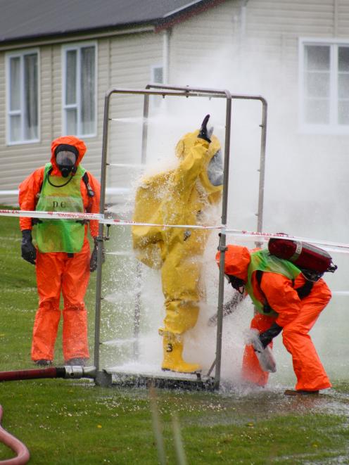 Fire service staff in decontamination equipment are washed down after attending a chemical spill...