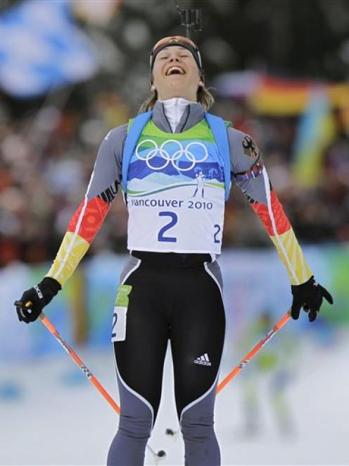 Germany's Magdalena Neuner smiles as she crosses the finish line to win the women's biathlon 10...