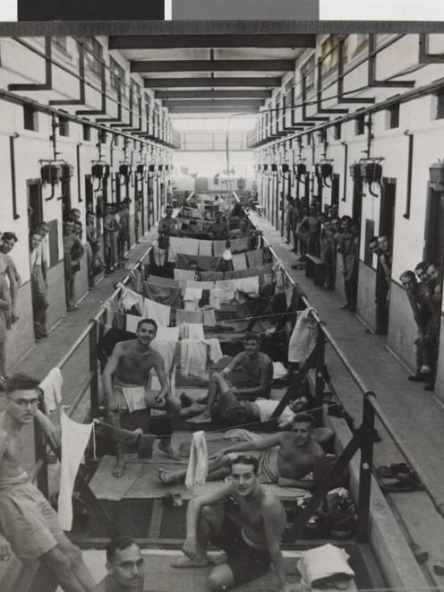 Liberated Allied prisoners lying in a corridor and looking out of cell doorways in Changi Prison,...