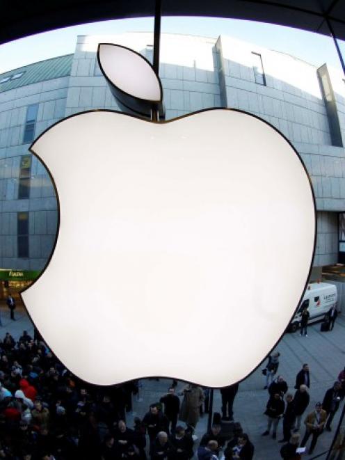 People wait on a street in front of an Apple store in Munich as they await sales of the new iPad...