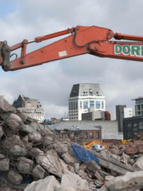 The Hotel Grand Chancellor is framed by an excavator and rubble at a dump in Tuam Street