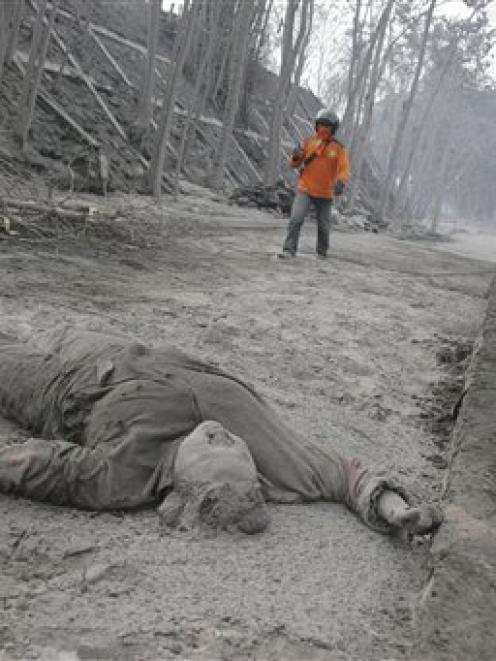 The body of a victim of Mount Merapi eruption lies on a road covered with volcanic ash as a...