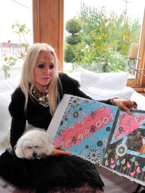 Victoria Davis, with her dog Panaish, looks through a scrapbook featuring her son, Jai Davis,...