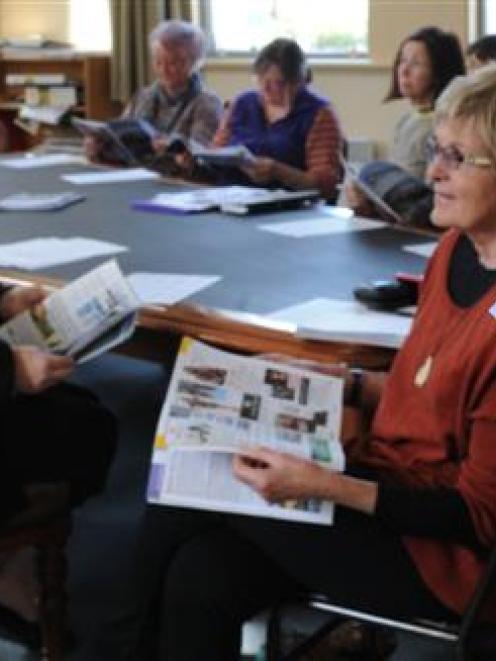 Volunteer cruise ship greeters are shown the new season's tourist information guide in Port...