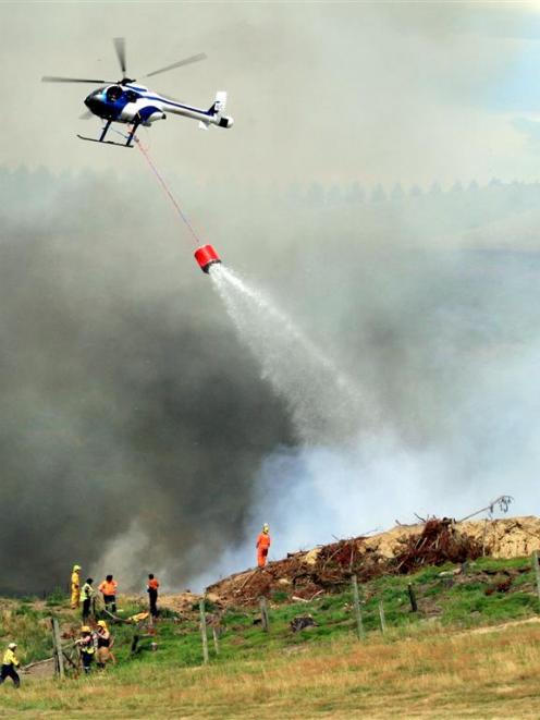 A helicopter carrying a monsoon bucket helps firefighters battle  a blaze  near Windsor yesterday...