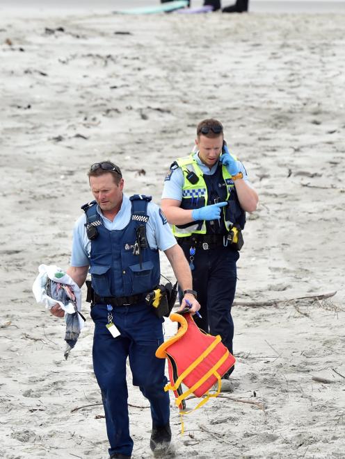 Police leave the beach with items recovered from the scene.