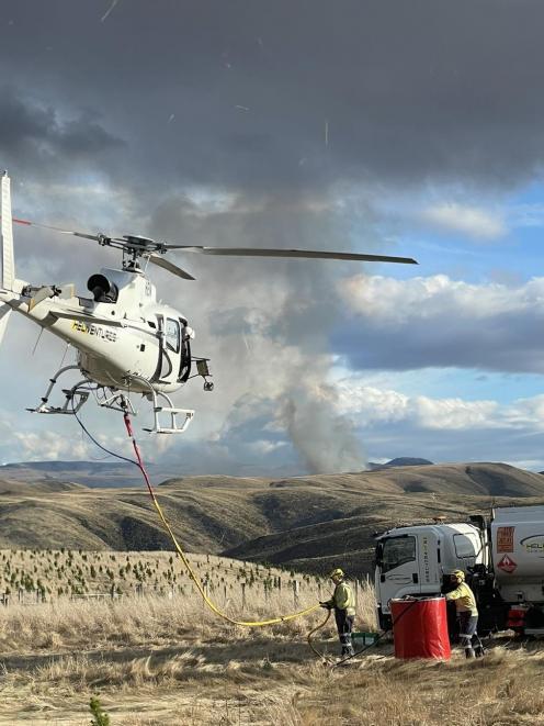 A Heliventures NZ helicopter tops up with the assistance of volunteer firefighters during last...