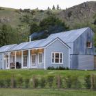 A restored weatherboard cottage, containing the main living areas,  sits in front of a new, two...