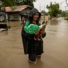 Jasper Miranda, 26, wades through floodwaters with his pet ducks that he saved from their flooded...