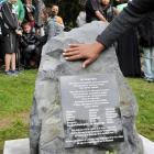 A hand touches a memorial stone during a ceremony at the Southern Cemetery in Dunedin yesterday....