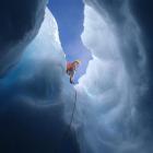 Antarctic field training instructor Jason Watson lowers a team member into an ice cave.