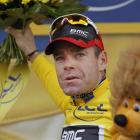 Cadel Evans of Australia throws flowers to cheering fans on the podium of the 20th stage of the...