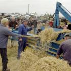 Tossing hay into a 1920s Booth Mac stationary baler is Ted Mills, with (from centre) Ronald Sheat...