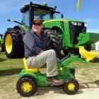 Grant Chalmers, from Southland Farm Machinery, sits astride a toy John Deere front-end loader,...