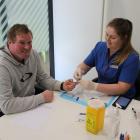 Gore dairy farmer Simon Vallely has his finger pricked by Southern Institute of Technology...