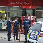 Police officers talk on the forecourt of the Caltex service station in Taieri Rd last night after...
