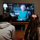 Noah (9) and Milly (7), of Hertford, watch Queen Elizabeth during a televised address to the...