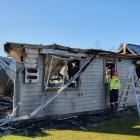 A Fenz firefighter checks on the remains of a house, off Tucker Beach Rd, in Queenstown, which...