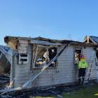 Fire fighters inspect the house that burnt in Queenstown. Photo: Matthew McKew