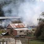 Fire crews assess the damage and dampen down the remains of a large shed that was destroyed by a...