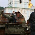 A boy poses for a photo standing on a destroyed Russian tank at a street exhibition of destroyed...