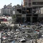 People walk among debris after an Israeli strike on Nuseirat refugee camp in the central Gaza...