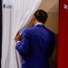 French President Emmanuel Macron heads into the voting booth during France’s first round of...