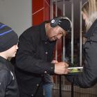 All Black loose forward Ardie Savea signs a photograph for young fan Zac Calvert, 9, and his...