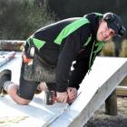 Dunedin builder Sacha Gray drills a hole on a building site. The cost to build a new house in New...