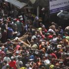 Palestinians gather to receive food cooked by a charity kitchen, near the ruins of houses...