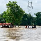 Rescuers ride a boat through a flooded area, searching for stranded people in Taungnoo city,...