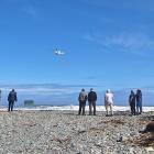 Police and onlookers watch as a rescue helicopter flies over Rapahoe Beach, where a man drowned...