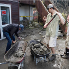 Jasper Thompson, middle right, shovels debris into a wheelbarrow as residents of Reavers Lane,...