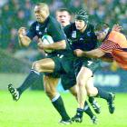 Jonah Lomu (L), followed by teammate Josh Kronfeld, breaks through a tackle from Scotland's Budge...