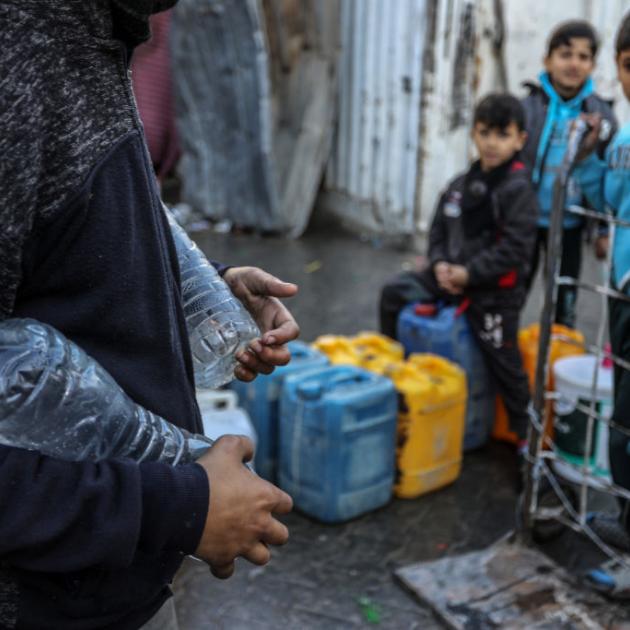 Palestinians carry containers of drinkable water collected from mobile barrels. UNRWA has been...