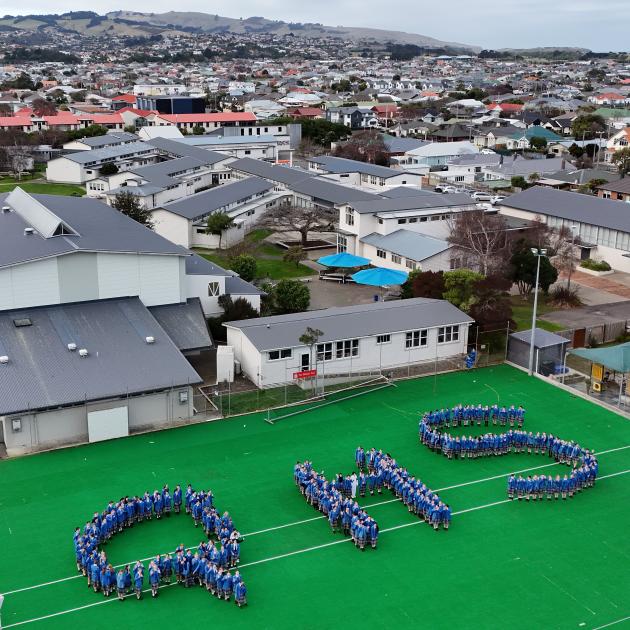 Queen’s High School year 9 and 10 students form the school’s initials on its turf. PHOTO: STEPHEN...