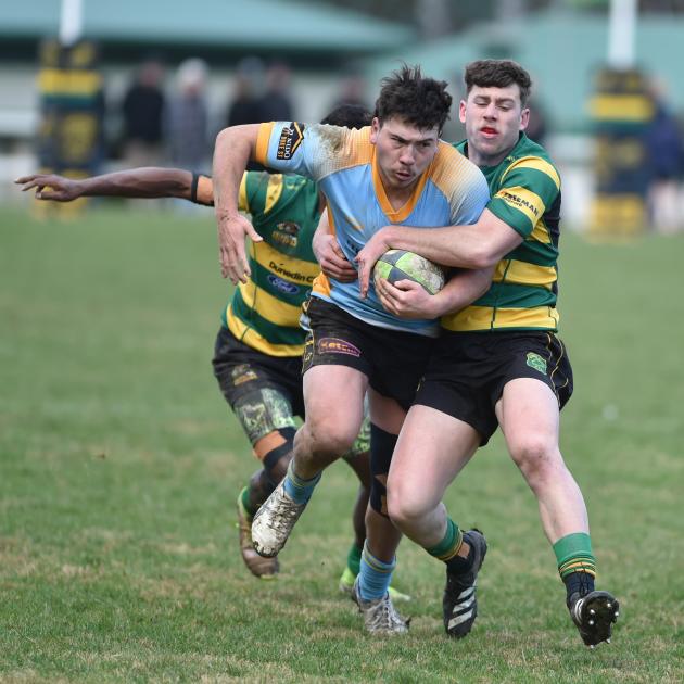 University winger Mac Harris is tackled by Green Island centre Riley Lucas, who has winger...