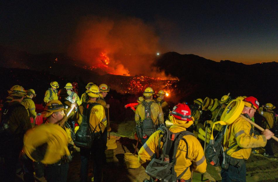 Firefighters work while smoke rises from the Palisades fire in Los Angeles. Photo: Getty Images