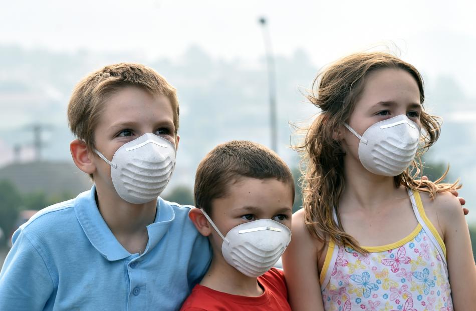 Tyler Drew (10, left), Logan Williamson (7) and Izabelle Williamson (10) in Clermiston Ave protect themselves from the smoke.